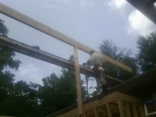 Carpenter setting a ridge beam over a new addition frame — Ice Dam Removal by Roofing Brothers in Capron
